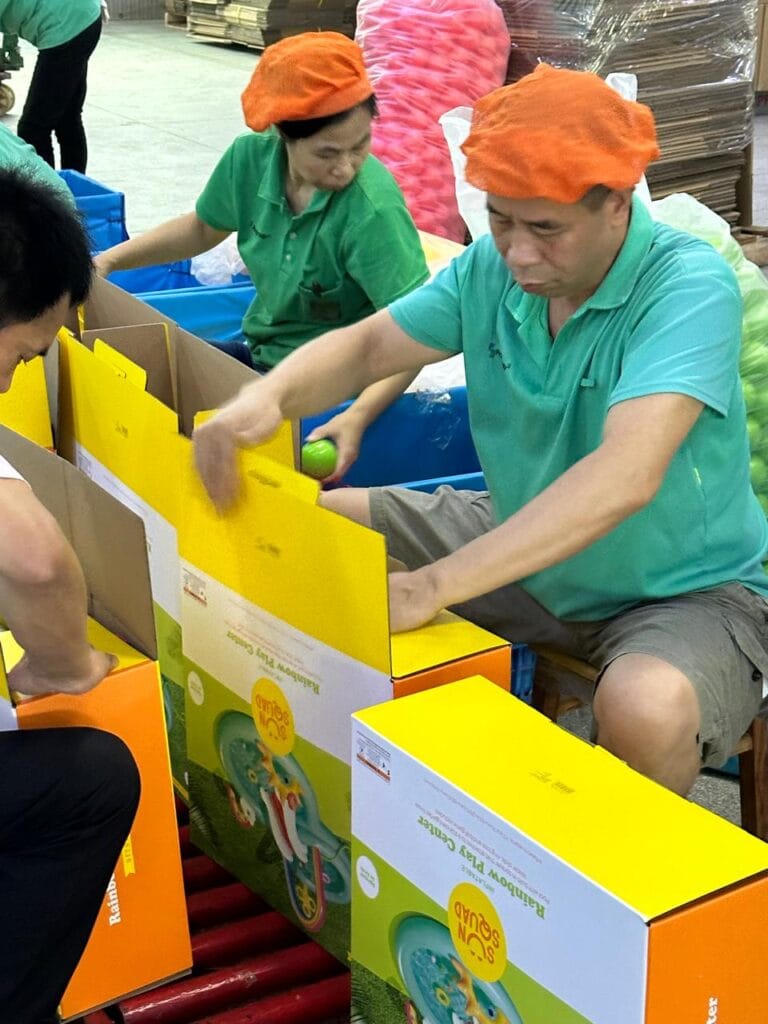Trabajadores empaquetando productos infantiles Sun Squad en una línea de producción dentro de una fábrica.